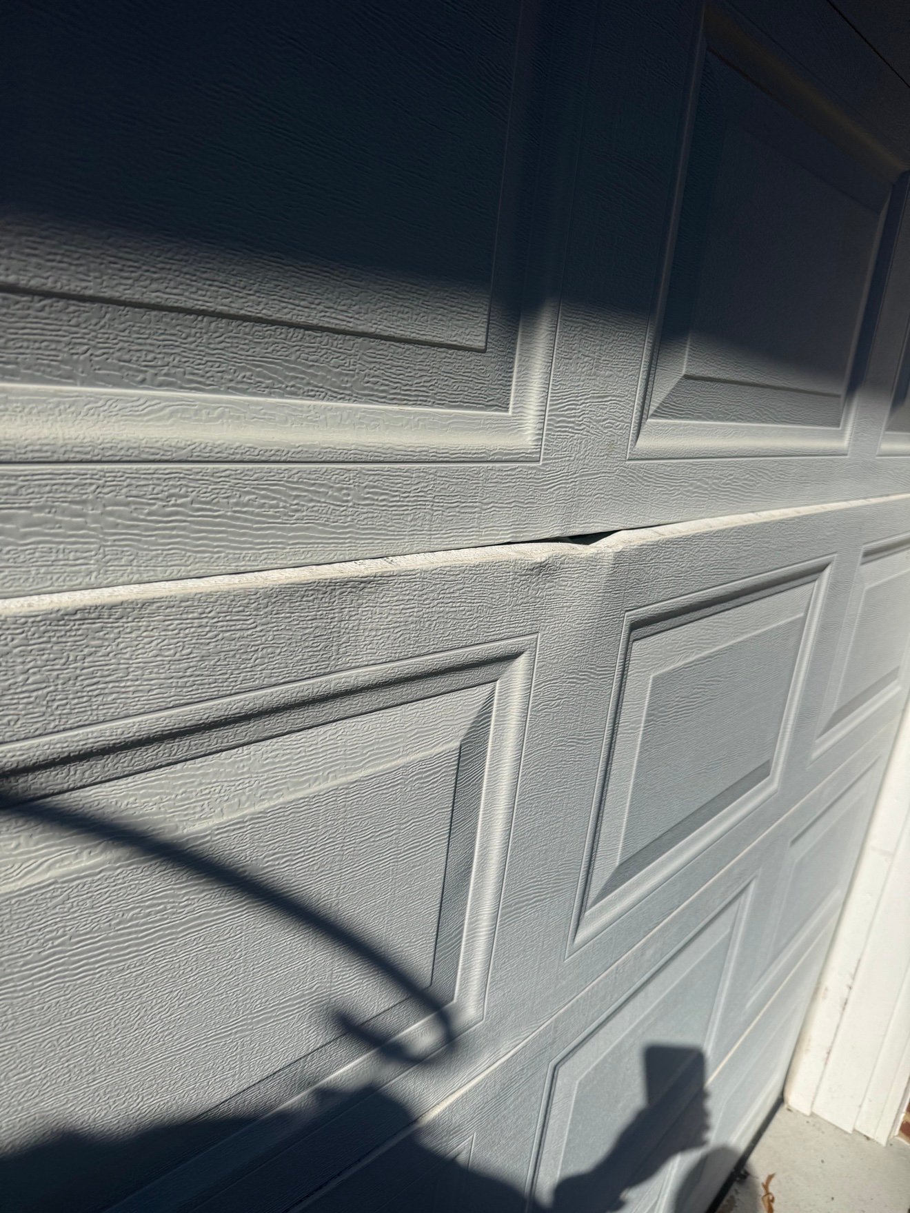 Dented garage door panel before repair